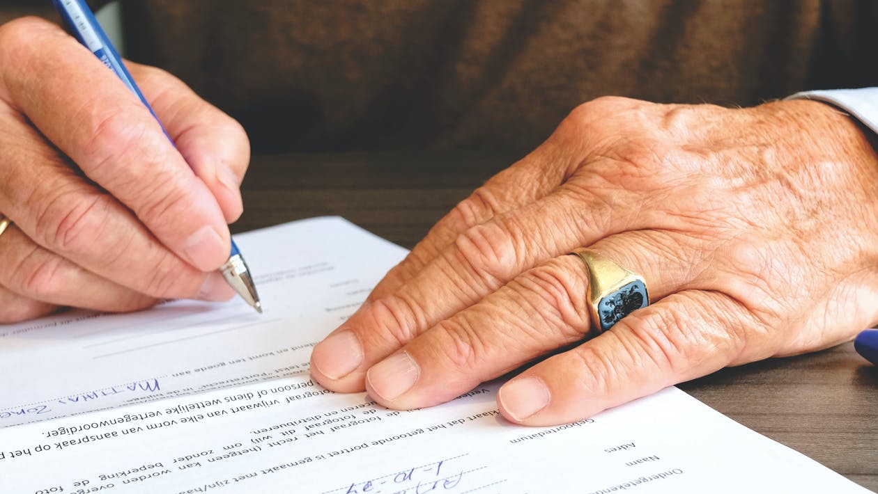 Old man hands signing estate planning documents
