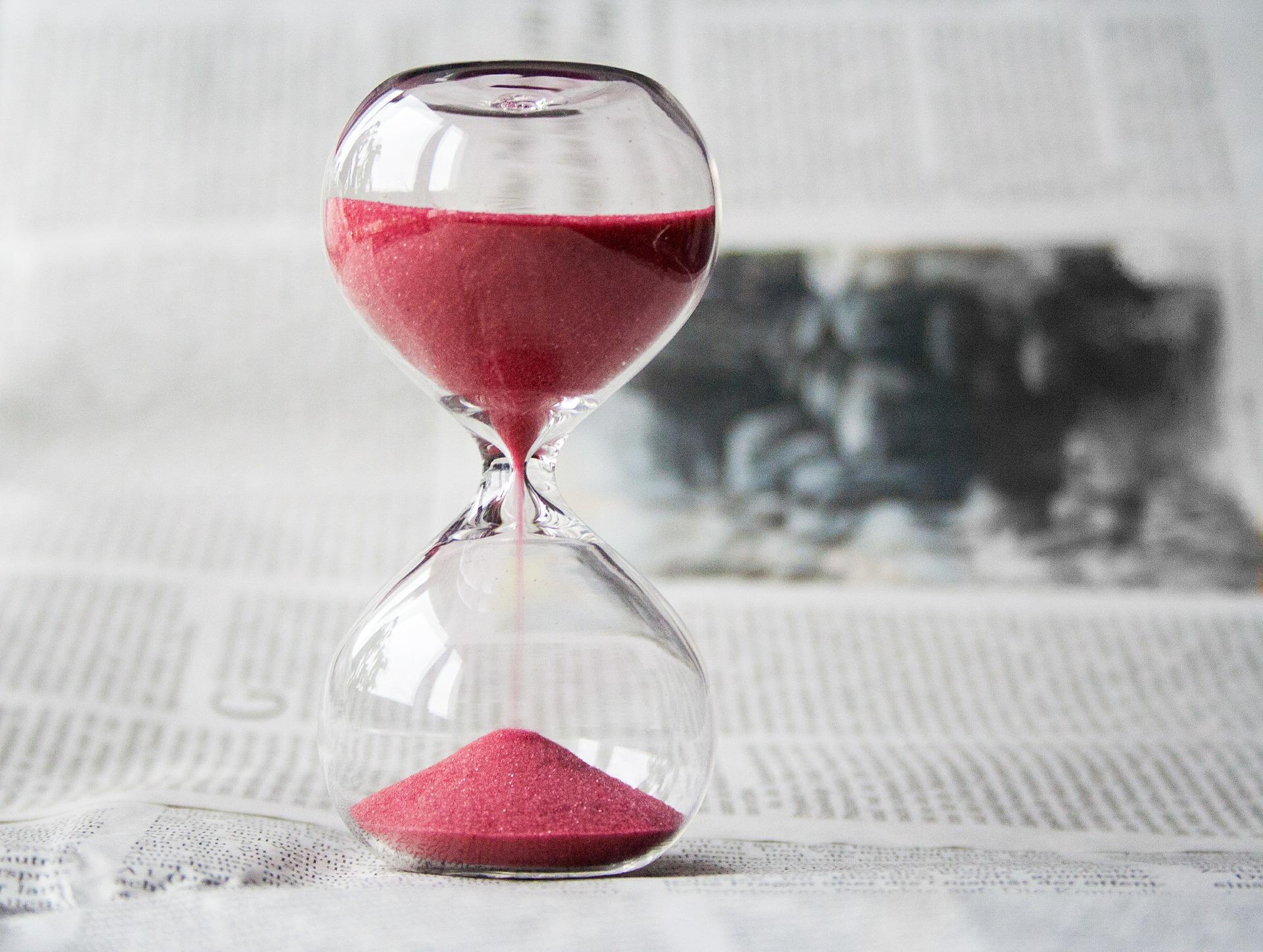 red sand hourglass on newspaper