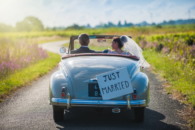 newlyweds driving away in car just married